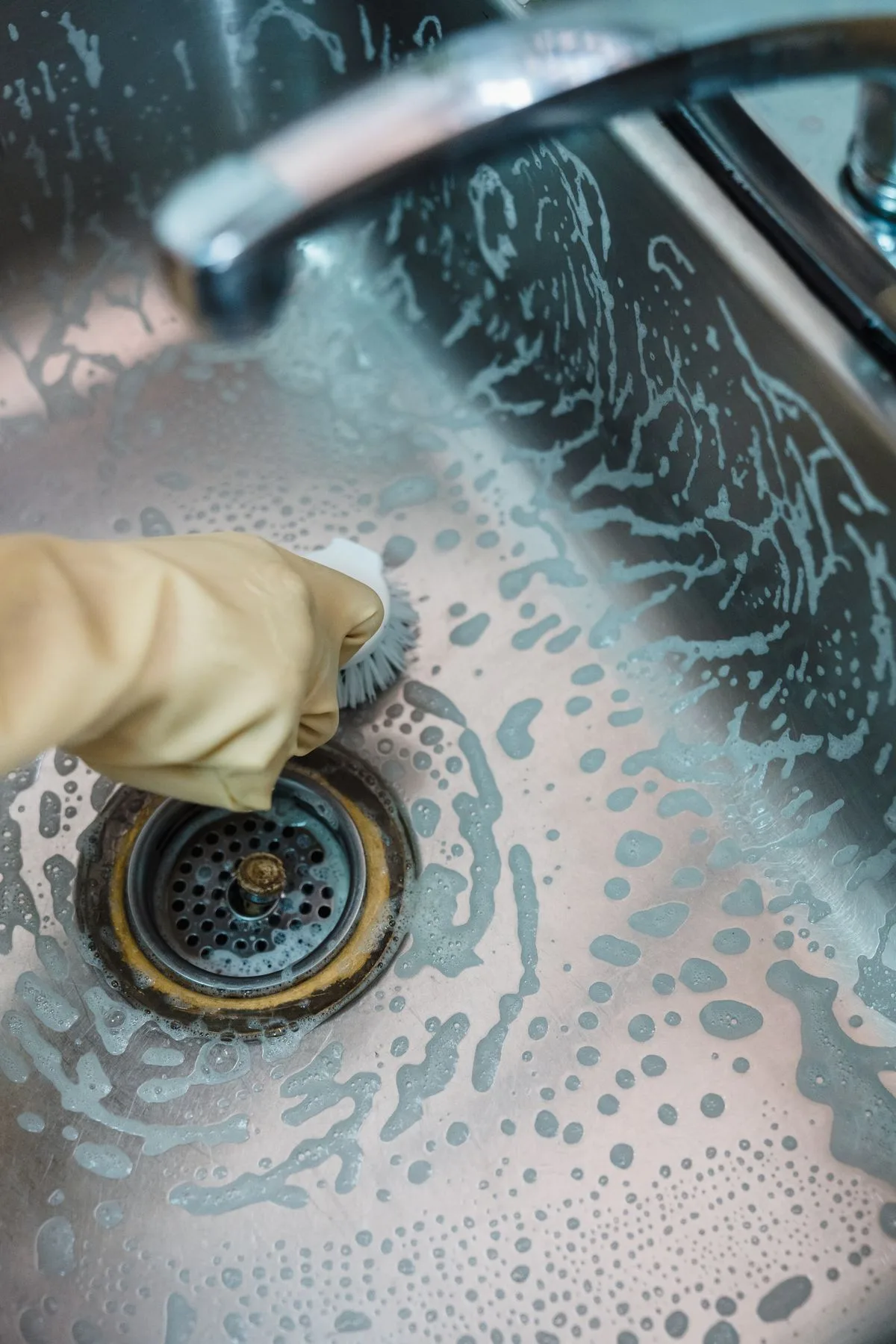 Professional plumber using a drain snake on a clogged sink